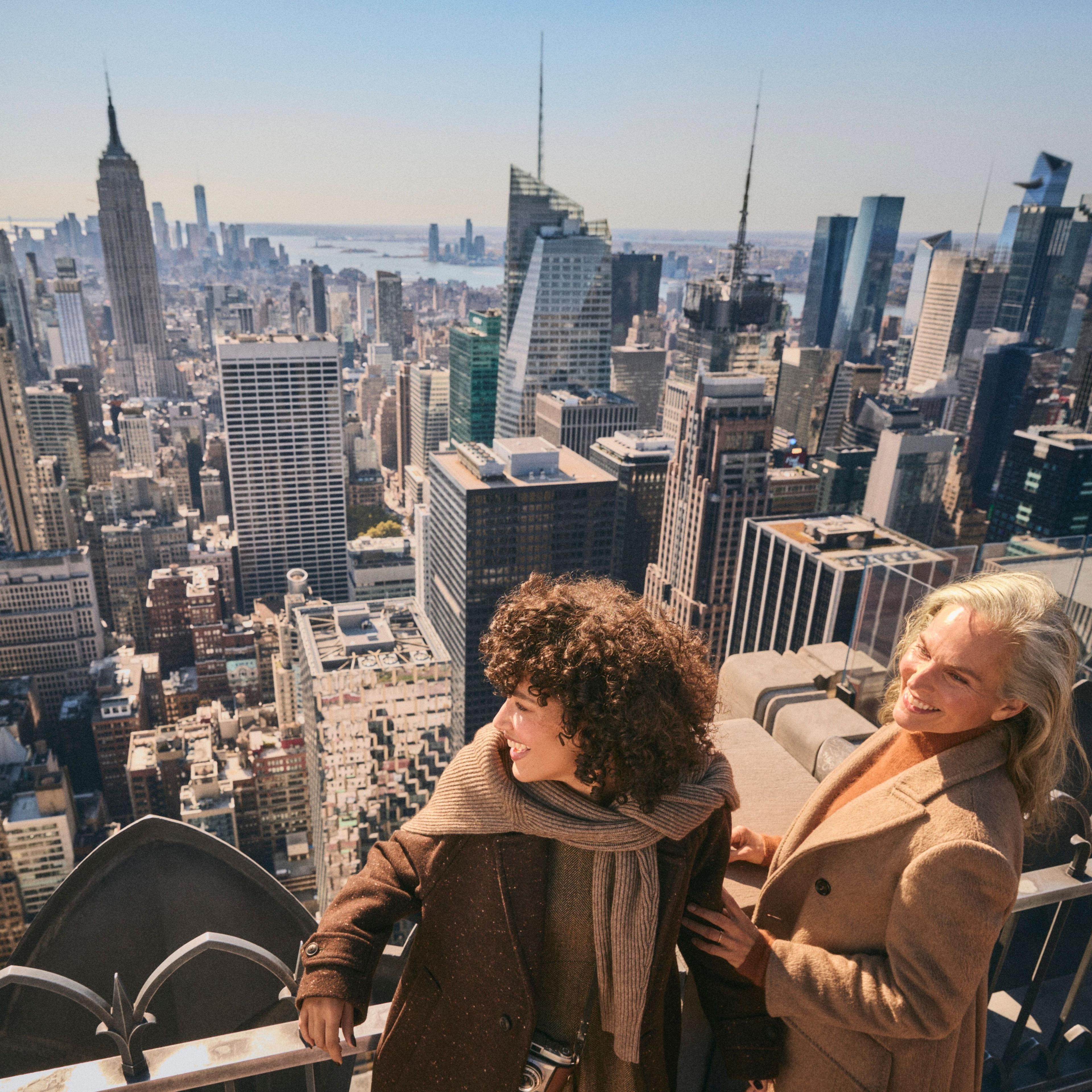two women smiling at top of the rock